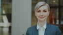 Smiling blonde businesswoman in a blue blazer in a modern office