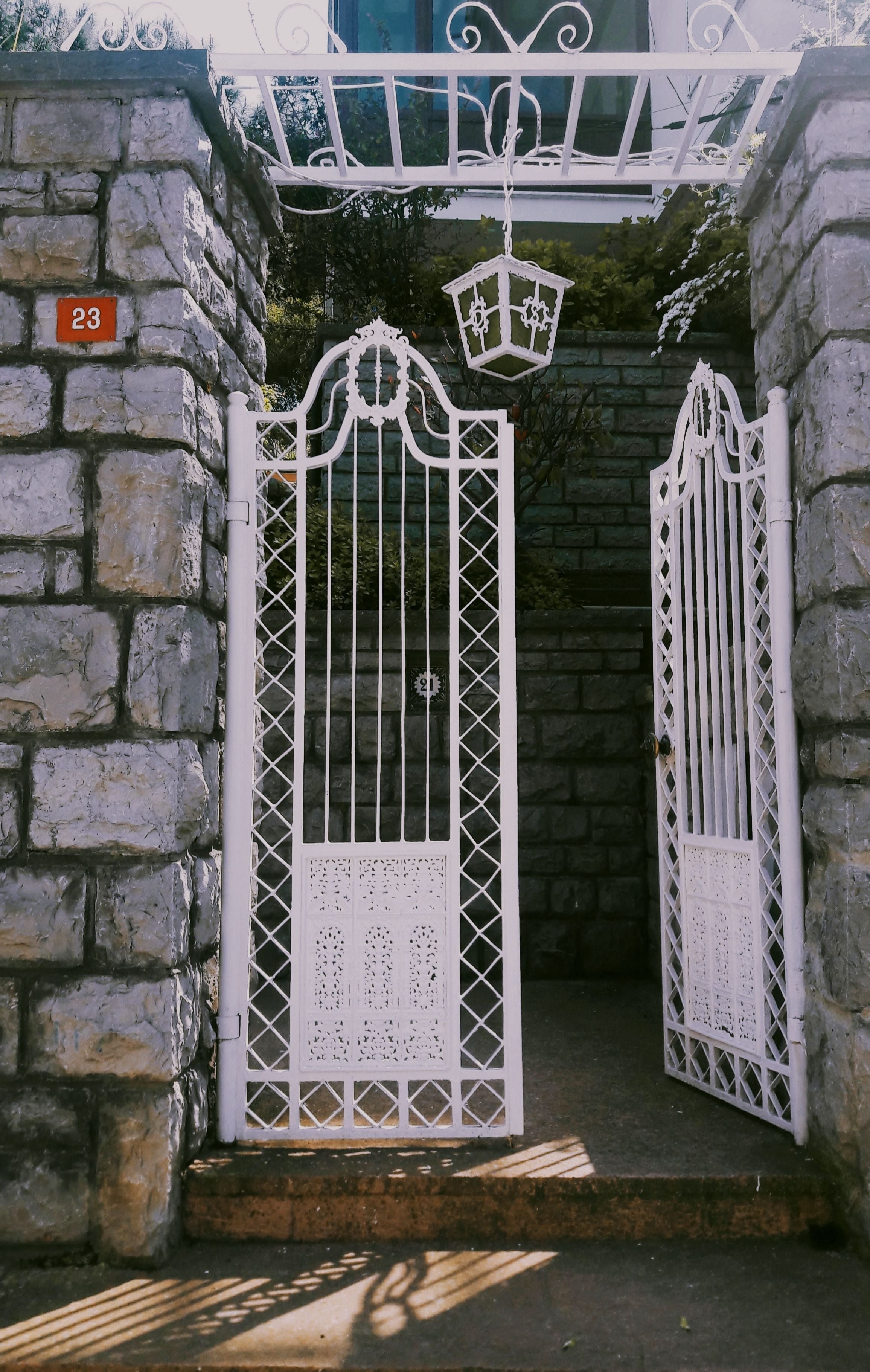 White wrought iron gate set in a stone entrance wall