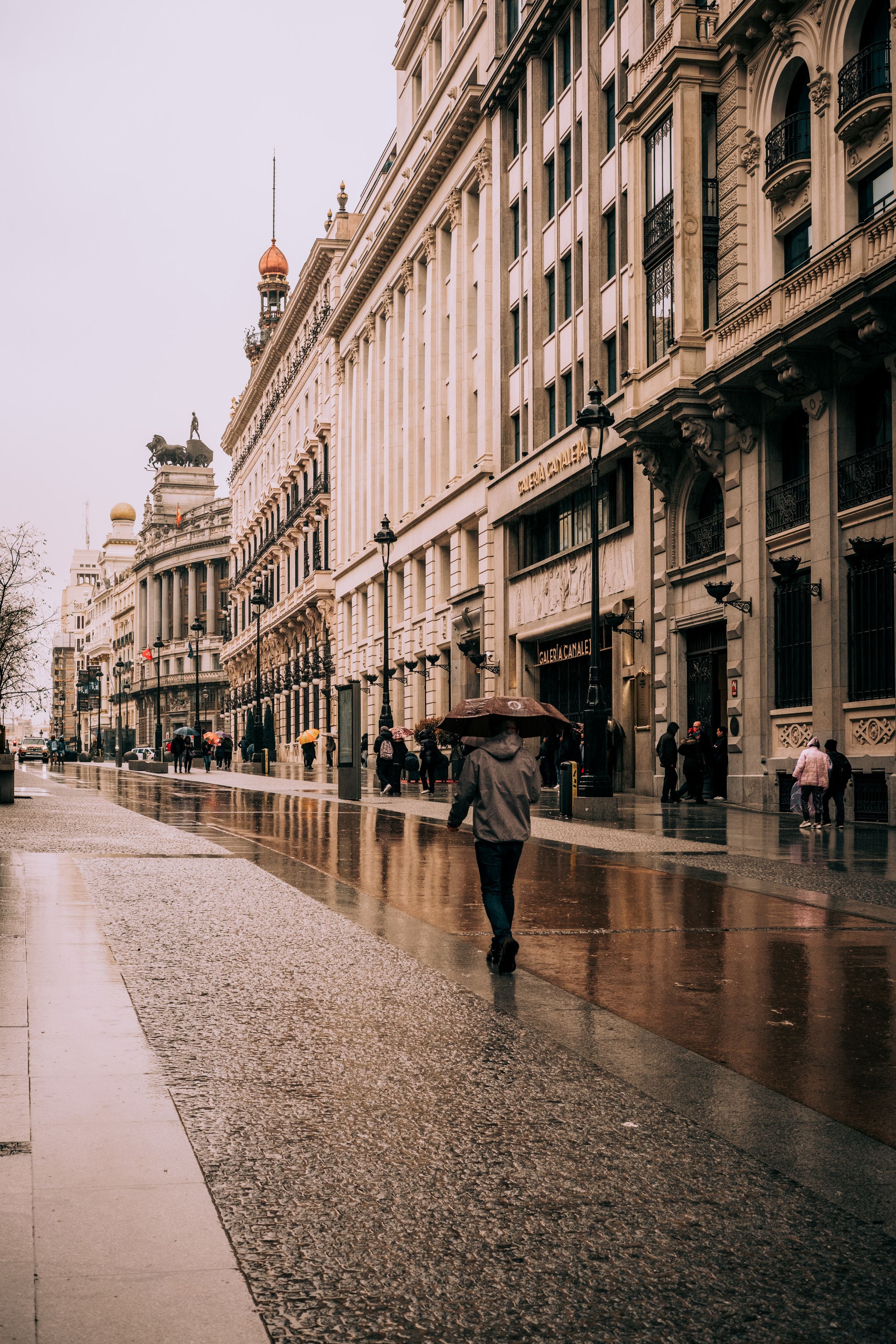 Gran Vía lined with classical apartment buildings on a rainy day in Madrid