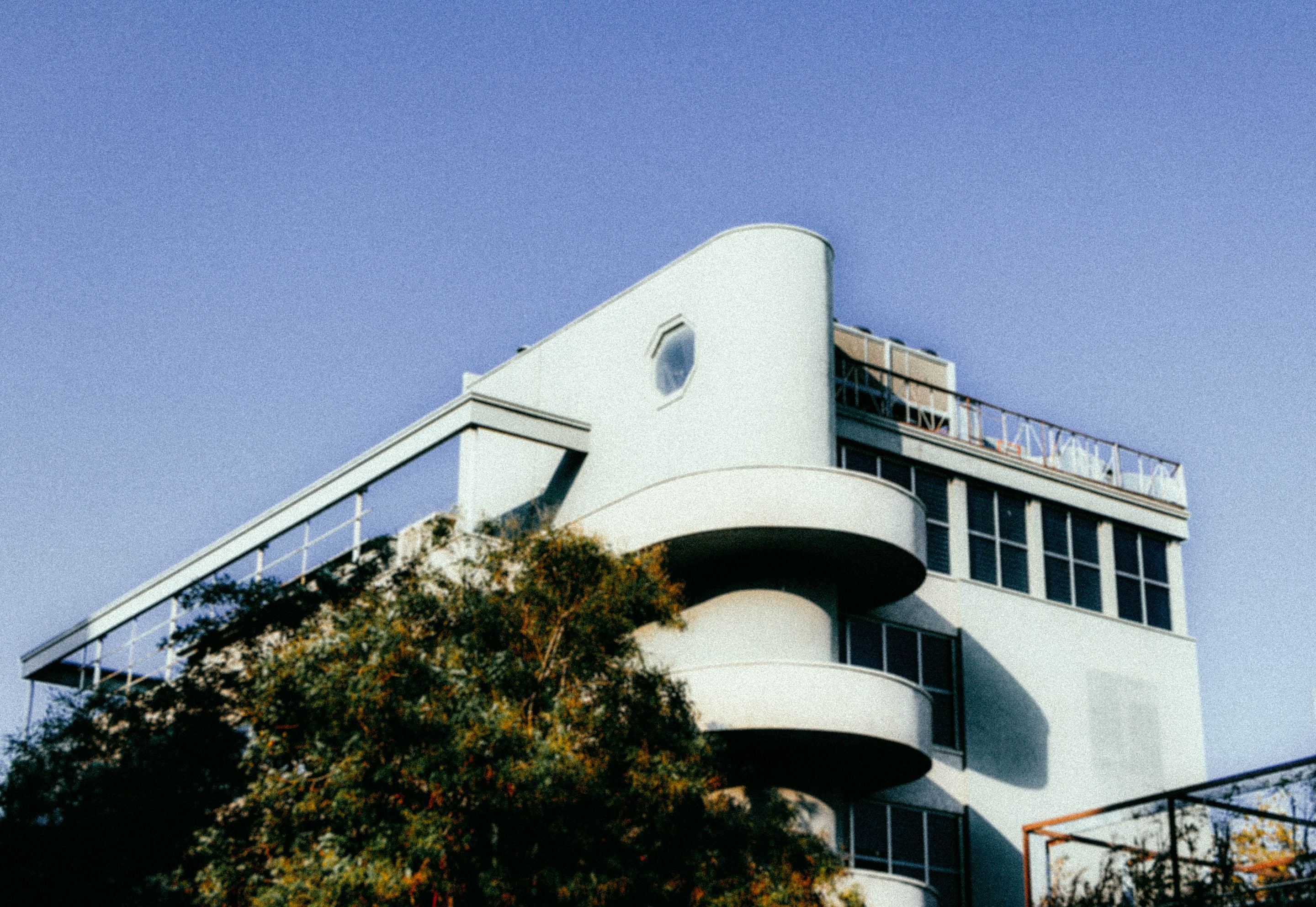 White Art Deco apartment building with curved balconies against a blue sky