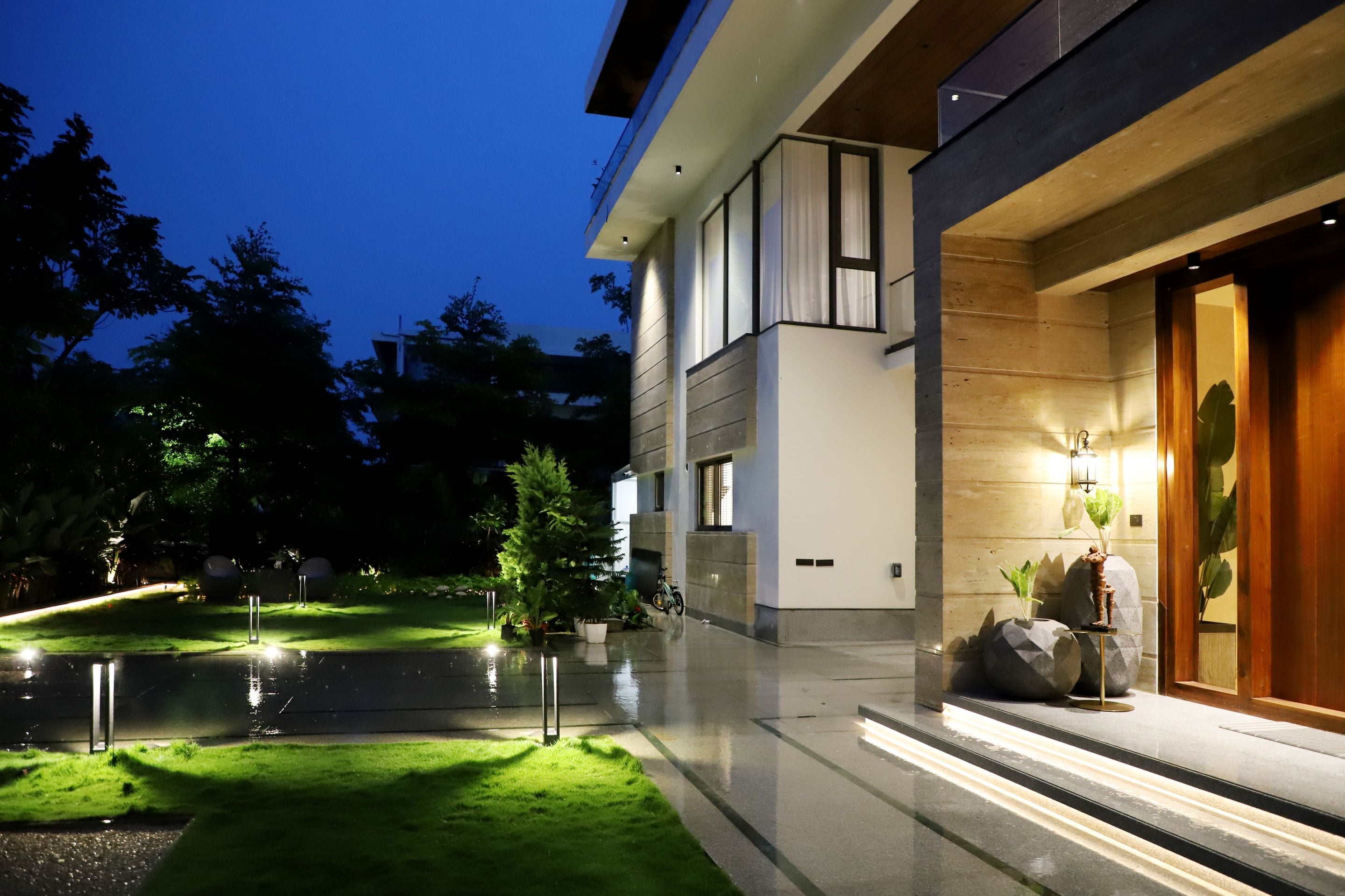 Contemporary home with timber door, uplighting and landscaped garden illuminated at night